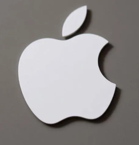 AirTag 2 resting on a white surface beside an iPhone displaying the Find My app showing firmware version 3.0.45 update details.