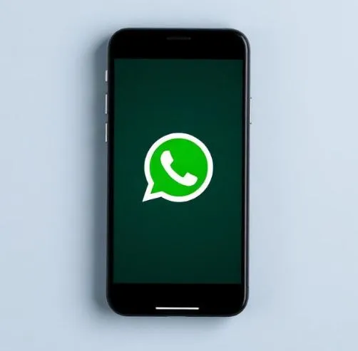  WhatsApp iOS in-chat screen showing Liquid Glass frosted-glass chat bar, transparent navigation bar, and blurred wallpaper background.